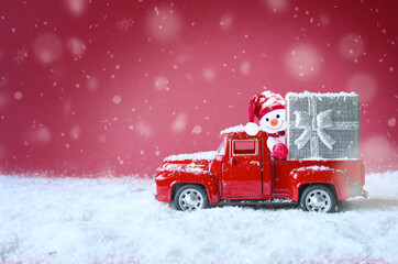 Christmas red background with snow, snowman and retro red car with gift box. .