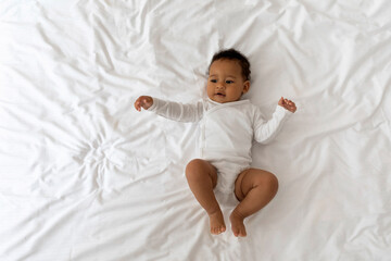 Top View Of Adorable Little Black Baby Lying On Bed At Home
