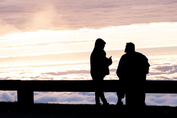 Fototapeta na wymiar Couple Sit on Guardrail Along Blue Ridge Parkway and Enjoy Cloud Inversion