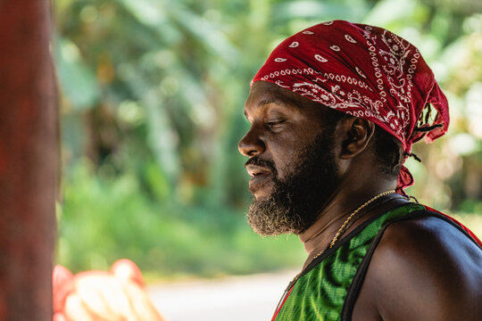 Retrato horizontal de cerca de perfil del rostro de un hombre afroamericano adulto solo con barba y utilizando un pa&ntilde;uelo en su cabeza al aire libre en un d&iacute;a de verano. 