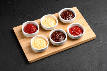 Sauces, different sauces on a wooden board on a black background