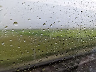 The landscape photo of rail train with field view. The photo take inside the train when rainy water drop. The photo is suitable to use for nature background, transportation back ground and advertsing.