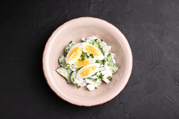 Salad with cucumbers, fresh salad with cucumbers and eggs on a black background