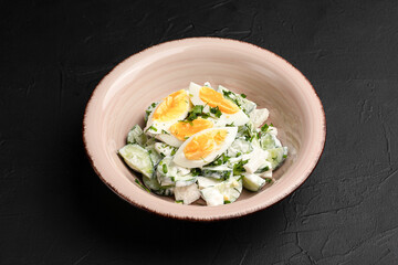 Salad with cucumbers, fresh salad with cucumbers and eggs on a black background