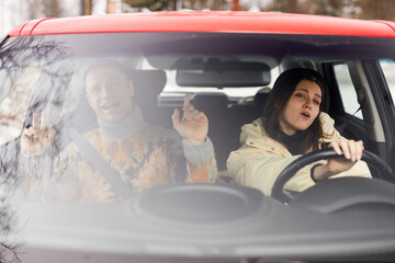 Portrait of carefree young couple singing in car while driving to winter vacation together