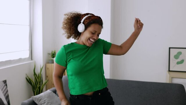 Young african ethnicity woman having fun alone dancing in living room. Millennial mixed race female celebrating enjoying free time at home. High quality 4k footage