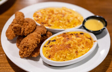 Plate of chicken fingers with accompaniment of macaroni and cheese