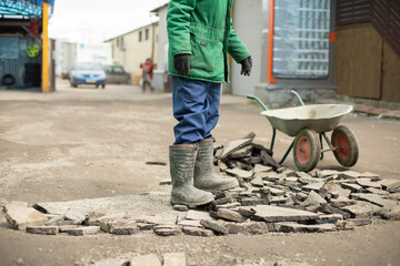 Guy makes road. Man at work. Worker stands on broken asphalt.