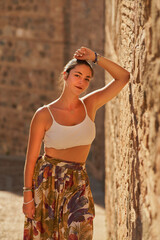 Latin girl with white top, skirt and ponytail posing happy in To