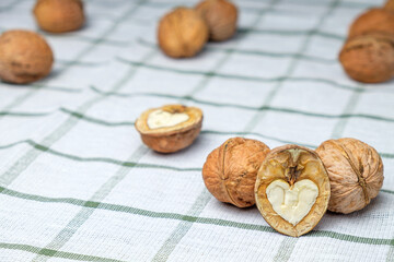 A heart-shaped cracked nut in the foreground, isolated on a beautiful white towel. Half a walnut. Background for the menu. Space for text