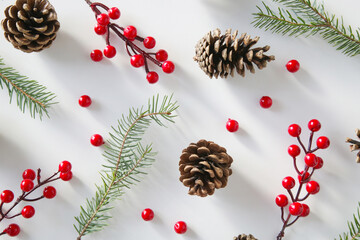 Fototapeta na wymiar Christmas tree branches, conifer cones and red berries, holiday cookies and ornaments, top view on white background. Christmas, winter holiday, new year concept.