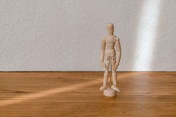 wooden model of a man in a beam of light on a white background