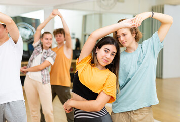 Positive teenagers dancing together slow ballroom dances in pairs in choreography class .