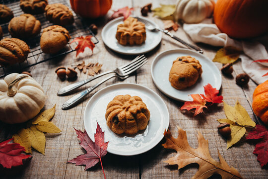 Close up of small autumn shaped pumpkin spice cakes on plates.