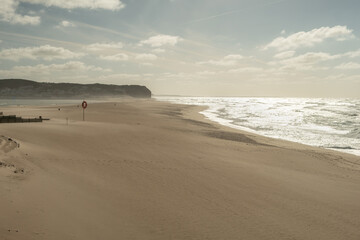 Beautiful golden sand with bright sun reflection in ocean water at Praia da Foz do Arelho in Portugal in summer
