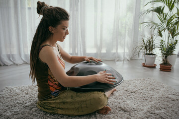 Woman playing a hang drum at home