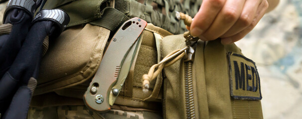 A soldier, a tactical medic opens a first aid kit, close-up view. - obrazy, fototapety, plakaty