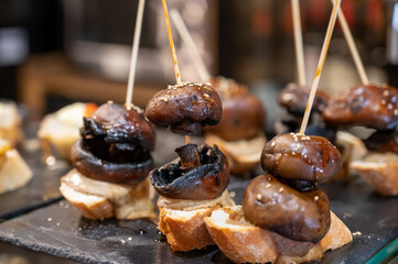 Typical snack is bars of Basque Country and Navarre, pinchos or pinxtos, small slices of bread upon which ingredient or mixture of ingredients is placed and fastened with skewers, San Sebastian, Spain