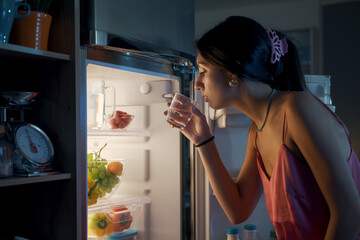 Fototapeta na wymiar Thirsty woman looking in the fridge at night