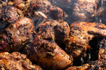 Grilling traditional Jamaican spicy jerk chicken with over charcoal fire.