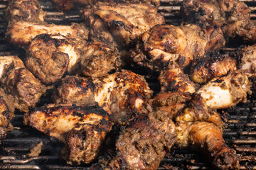Grilling traditional Jamaican spicy jerk chicken with over charcoal fire.