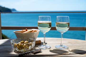 Txakoli or chacolí slightly sparkling very dry white wine produced in the Spanish Basque Country, served outdoor with view on Bay of Biscay, Atlantic Ocean.