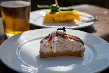 Sunny day in San Sebastián, typical food and drink in bars of Basque Country, pinchos or pinxtos, small slices of bread with different toppings and glass of beer, lunch in Spain