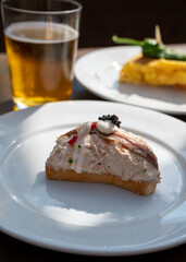 Sunny day in San Sebastián, typical food and drink in bars of Basque Country, pinchos or pinxtos, small slices of bread with different toppings and glass of beer, lunch in Spain