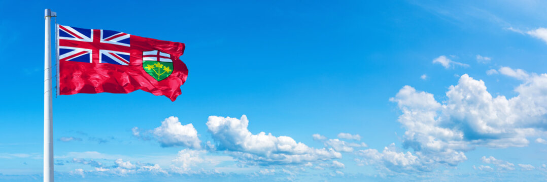 Ontario - Canada flag waving on a blue sky in beautiful clouds - Horizontal banner
