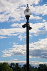 Fototapeta na wymiar Street lamp before bright cumulus clouds