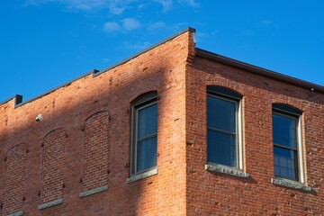 Obraz premium Brick mill building corner roofline against bright blue sky in Haverhill downtown