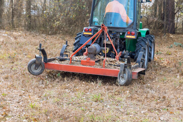 Obraz premium During autumn tractor is used to trim remove small branches that have grown there