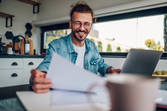 Young business man working at home with laptop and papers on desk