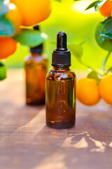 tangerine essential oil.Mandarin oil.Natural organic pure oil. brown bottles with oil on a brown wood background and tangerines with green leaves.Organic natural eco cosmetics.
