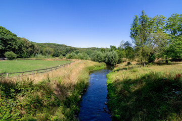 Fototapeta na wymiar Summer landscape view with Geleenbeek river with trees and grass along the water, Spaubeek is a village in the Dutch province of Limburg, It is located in the municipality of Beek, Netherlands.