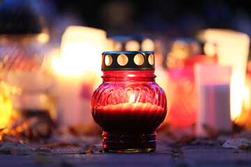 Świeczka na grobie osoby bliskiej świeci podczas święta zmarłych. - obrazy, fototapety, plakaty