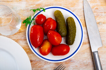 Pickled tomatoes and cucumbers on plate, homemade preserves