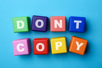 Plagiarism concept. Phrase Don't Copy made of color cubes with letters on light blue background,...