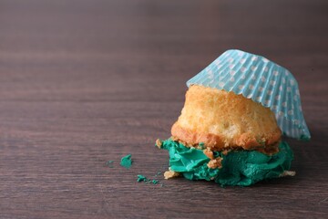 Dropped cupcake with cream on wooden table, closeup. Troubles happen