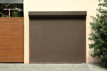 Building with brown roller shutter garage door on sunny day