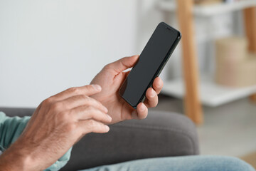 Man using smartphone at home, closeup view