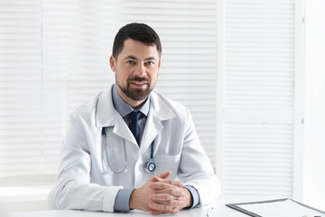 Portrait of male doctor in white coat at workplace