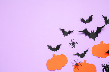 Flat lay composition with paper bats, spiders and pumpkins on light violet background, space for...