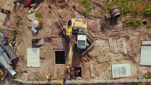 Demolition construction working site. An excavator performing lifting operations. Underground pipe work. Warsaw. Top drone view. High quality 4k footage