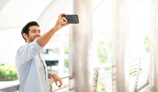 The young man selfies with himself using a smartphone to take photos, and waits for his friend.