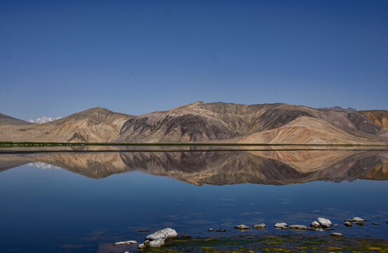 Reflecting rainbow mountains on Lake Bulunkul, Pamir Highway, Tajikistan