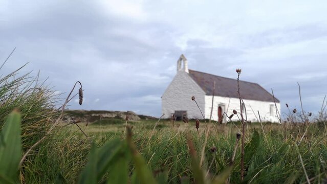 Medieval Eglwys St Cwyfan white church on windy Anglesey island causeway