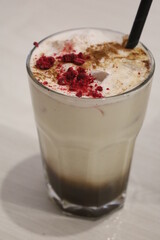 Iced chai latte beverage. Cold drink for morning breakfast. Ice cubes, raspberry and coffee topper. 