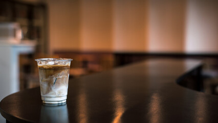 Ice coffee on a plastic cup with cream being poured into it showing the texture