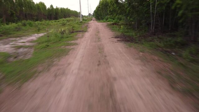 Point of view footage while driving down a road in rural. Car driving fast on a dirt road among the trees in summer.